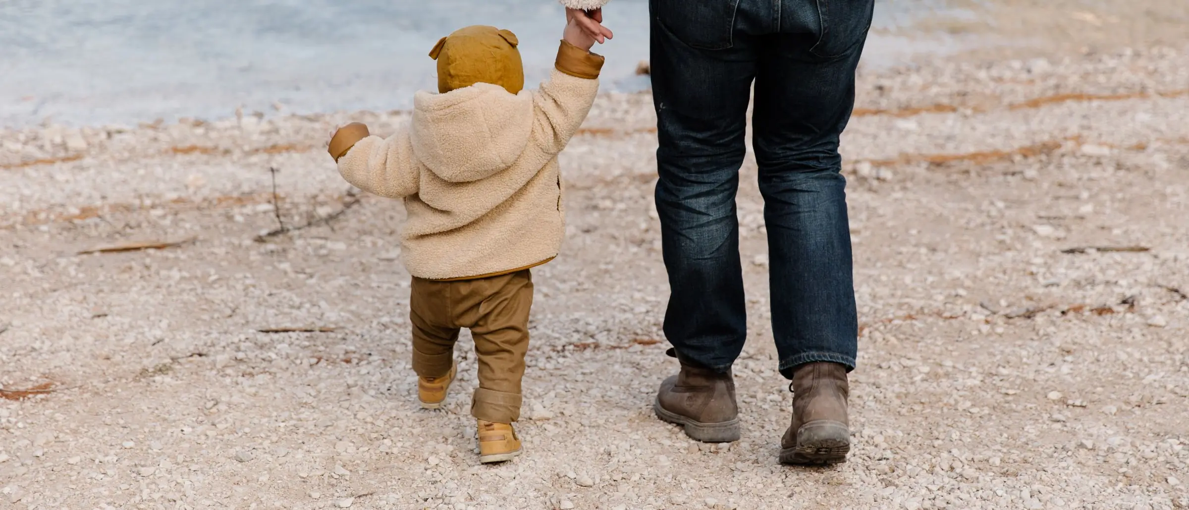 Papá caminando de la mano con su hijo pequeño a la orilla del mar